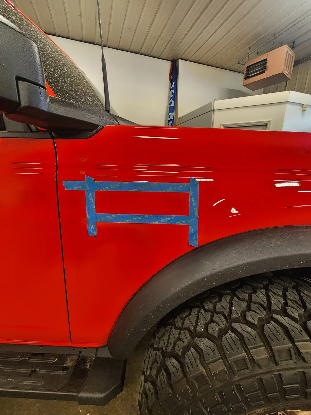 Side view of a red Ford Bronco during the paint protection film (PPF) prep process at Valion Tinting, showcasing meticulous surface measurement and protection expertise in Kansas City